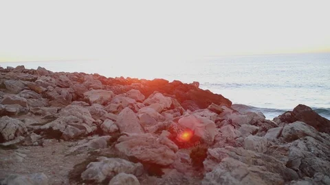 A ray of rising sun glides over the rocky cliffs of the shore Stock Footage 130022358