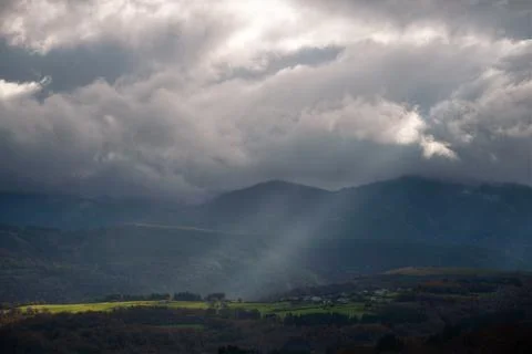 A ray of sun breaks through the clouds and illuminates some meadows Stock Photos