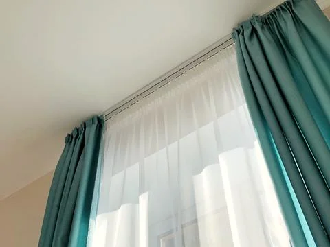 Ray of sun lighting through transparent curtain on window into bedroom Stock Photos