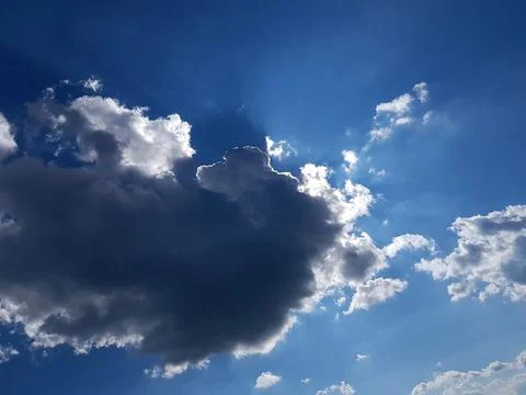 A ray of sun peeks through a dark cloud. Dark cloud in the sky. Sun from a cloud Stock Photos