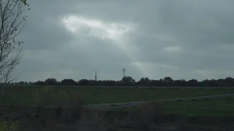 Ray of sunlight breaks through clouds to illuminate a quiet levee and telecom to Stock Footage 324373340
