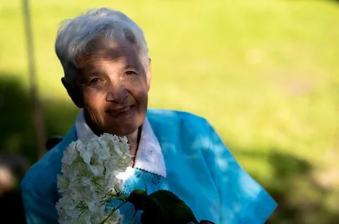A ray of sunlight on the face of an smiling old woman looking at camera Stock Photos