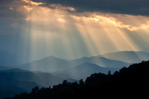 Ray of sunlight shining through clouds to mountains. Stock Photos