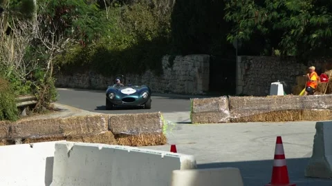 Ray Vella Jaguar D‑Type no. 11 slow‑motion cornering on Mdina street circuit Video stock 324934785