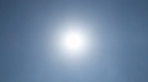 Rayed sun behind a thin mist in blue sky Stock Footage