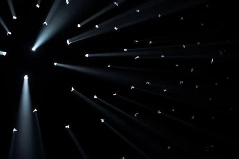 Rays of bright light come through holes in the black background of the studio Stock Photos