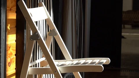 Rays of bright sun fall on wooden chair on background of dark walls. Stock Footage 108000769