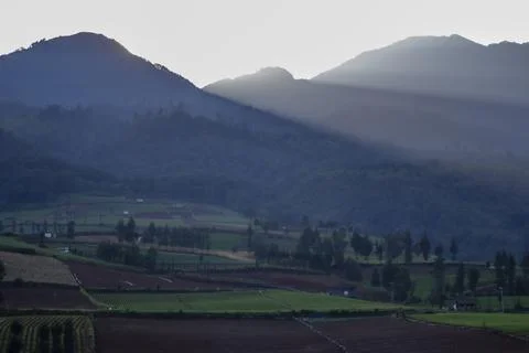 Rays of light come out from the mountain and shine the agricultural valley Stock Photos