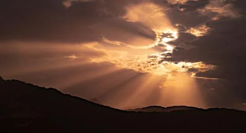 Rays of light filtering through the clouds in a beautiful sunset or sunrise b Stock Photos