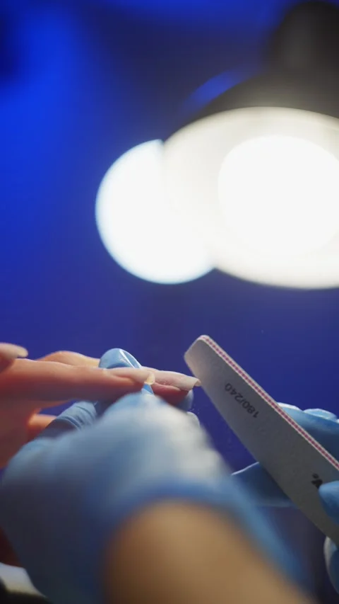 In the rays of light from the lamp, the manicurist creates the perfect nail. Video stock 325307086