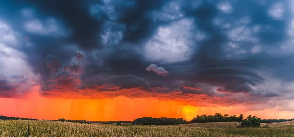 Rays of light shine down from a cloudy sky into a fields. Sun beams bursting Stock Photos