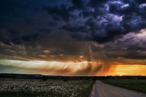 Rays of light shine down from a cloudy sky into a fields. Sun beams burstin.. Foto stock