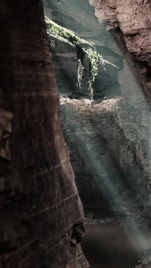 Rays of light shine through rocks in a canyon during daylight hours Stock Footage 339508334