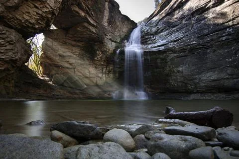 Rays of light through a rock and a waterfall Foto stock