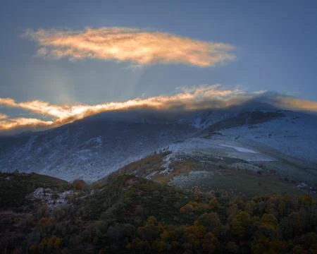 Rays of the Rising Sun pass through the Clouds that crown the Mountains Stock Photos