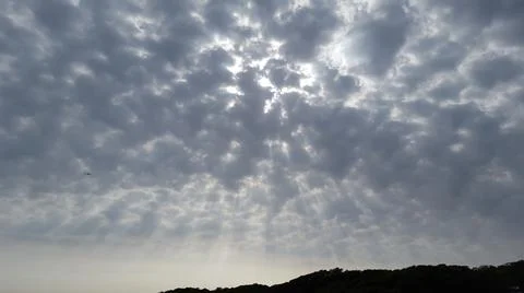 The rays of the setting evening sun through the clouds. Cloudy sky. Stock Photos