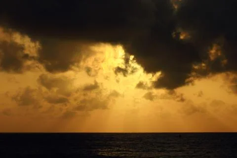The rays of the setting sun breaking through the dense clouds Stock Photos