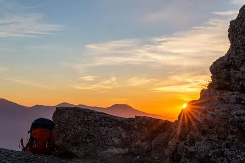 The rays of the setting sun make their way through a piece of rock and a trav Stock Photos