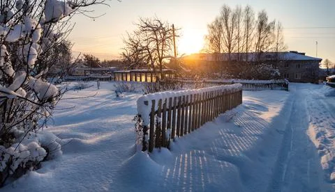 The rays of the setting sun shine through the picket fence, creating beautifu Stock Photos