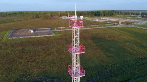 In the rays of the setting sun, a working assembler stands on a high iron tower Stock Footage 155516639
