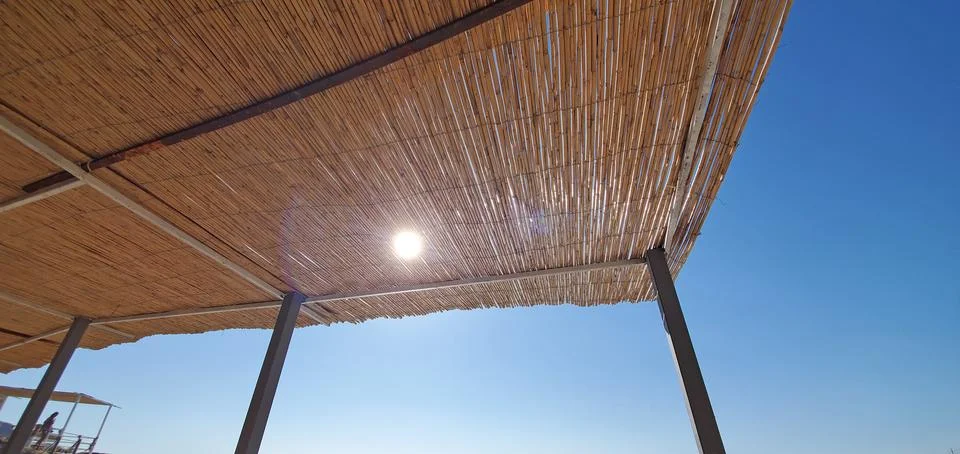 The rays of the summer sun break through the thatched roof of the bungalow Stock Photos