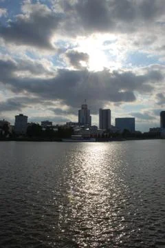 Rays of the sun coming through clouds over the buildings near the river Stock Photos