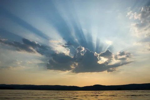 Rays of sun light breaking through from behind the clouds with nice contrast Stock Photos