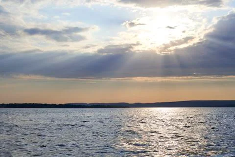 The rays of the sun make their way through the clouds on the river landscape Stock Photos