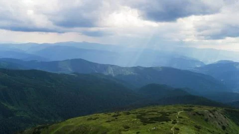 The rays of the sun make their way through the stormy sky in the mountains Stock Photos