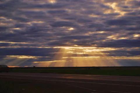 The rays of the sun make their way through the evening sky in the steppe Stock-Fotos