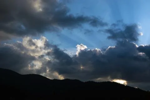 Rays of the sun making their way through the clouds against the backdrop of t Stock Photos