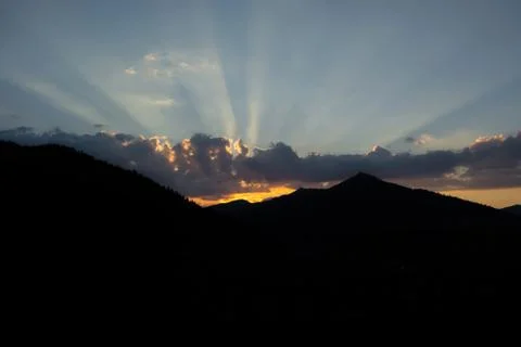 Rays of the sun making their way through the clouds against the backdrop of t Stock Photos