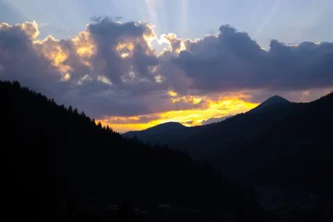 Rays of the sun making their way through the clouds against the backdrop of t Stock Photos