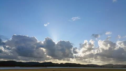Rays of the sun shine over dark clouds on the blue sky background Stock Photos