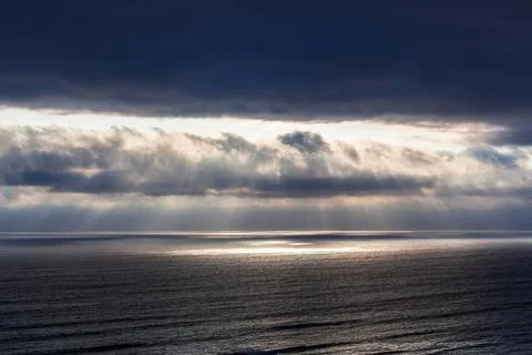 Rays of sun through the clouds over ocean Stock Photos