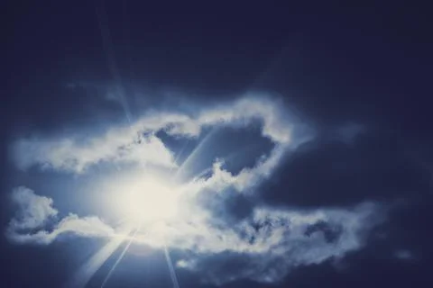 Rays of the sun through dark blue heavy clouds, sunlight. Sunbeams break thro Stock Photos