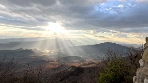 Rays of sunlight illuminate a valley with a river among the mountains 動画素材 257417372