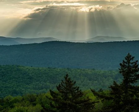 Rays of sunlight pour through the clouds over the mountains Stock Photos