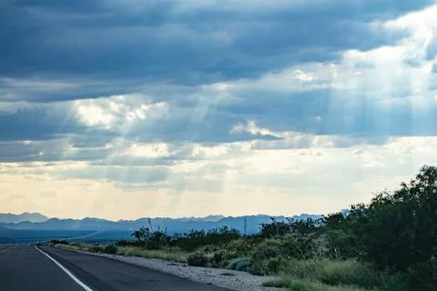 Rays of sunlight through clouds shine down on texas hills and plant life Foto stock