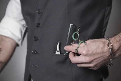 .razor, comb and scissors on hand in the barber's pocket Stock Photos
