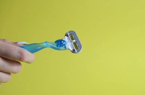 Razor in hands on a yellow background. Stock Photos
