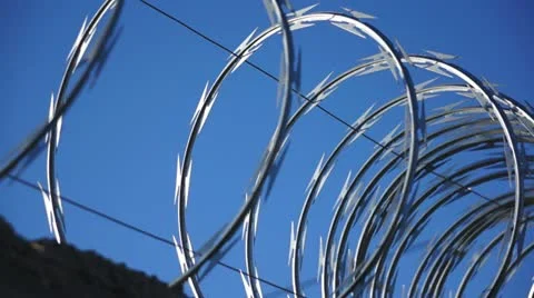 Razor Wire Close Up Pan Against a Blue Sky Stock Footage 20468599