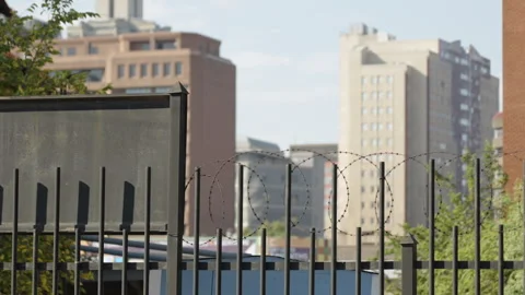 Razor Wire Security Fence with Downtown High-Rise Background Stock Footage 343892323