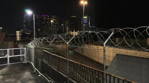 Razor Wire Security Fence at Night with Illuminated Kuala Lumpur Skyline 스톡 동영상 343475525