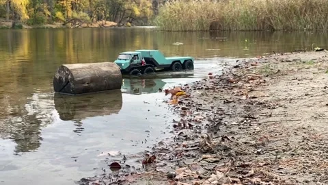 RC flatbed towing truck going on ponds shallow water. Stock Footage 207410327