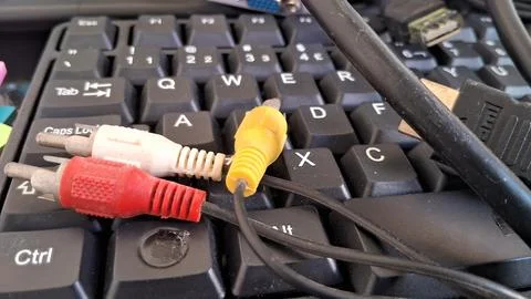 RCA audio video cables on a computer keyboard. Analog connectors resting on PC Foto stock