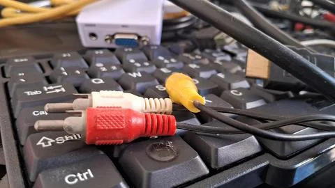 RCA cables on a computer keyboard. Audio video connectors resting on a PC Foto stock