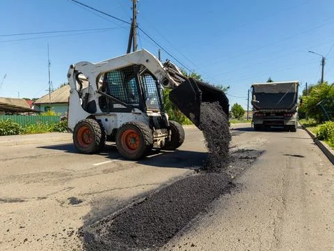 A re -control loader drops asphalt on the side of the road Stock Photos