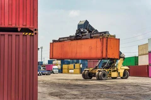 Reach stacker lifting shipping container in freight yard terminal logistics.. Fotos Stock