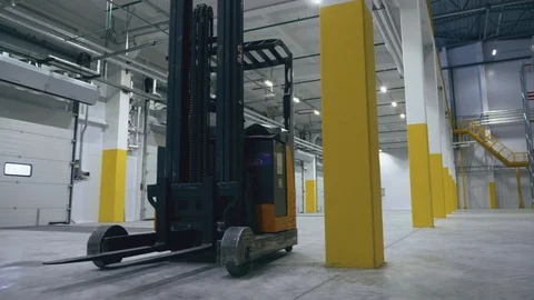 A reach truck in an empty logistic center rides between columns Video stock 104361853